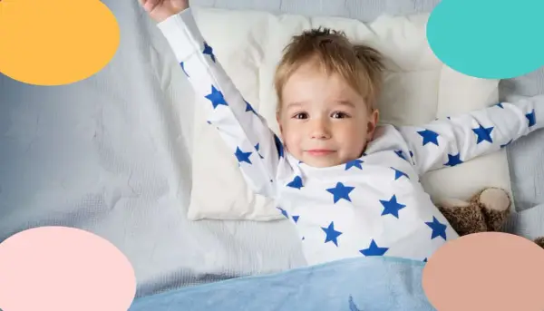 Niño de 3 años, con pijama de estrellas, estirándose en la cama.