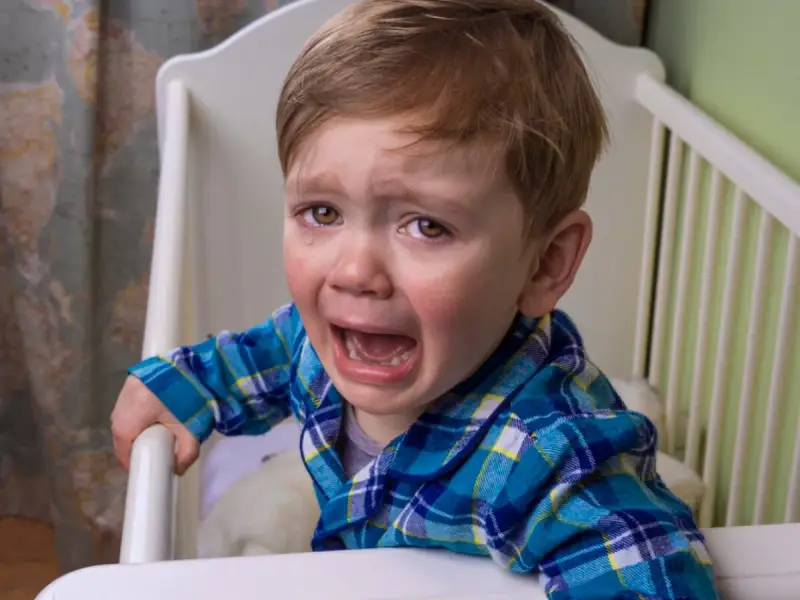 Niño de 10 años llorando en su cuna, se comporta como bebé.